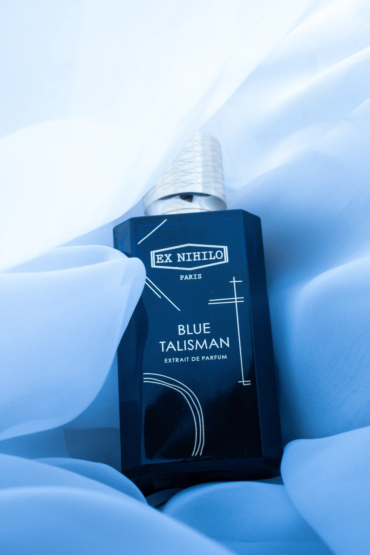 Ex Nihilo Blue Talisman Extrait fragrance bottle on blue silk — guest memento at the Salon Privé show