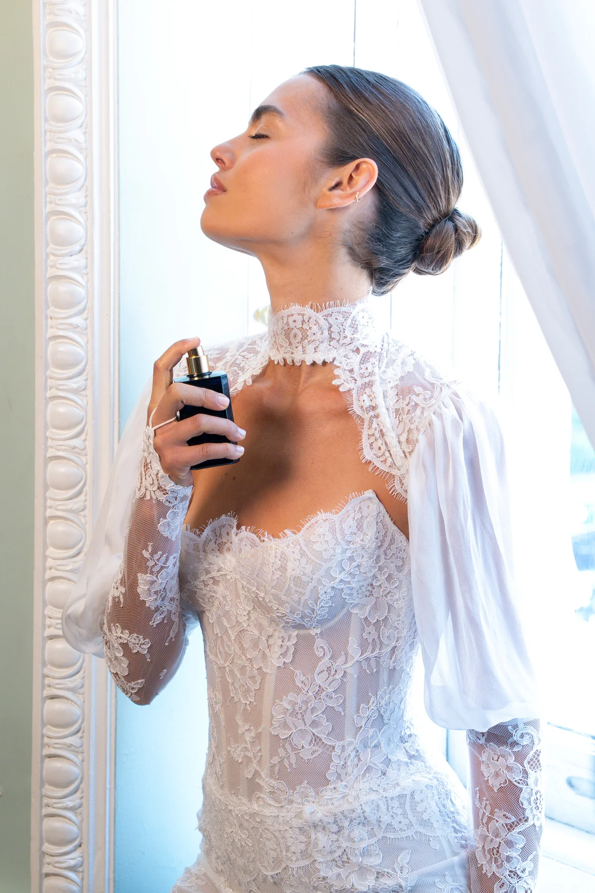 Lee Petra Grebenau bride in a high-neck lace gown spraying Ex Nihilo Blue Talisman fragrance before the runway